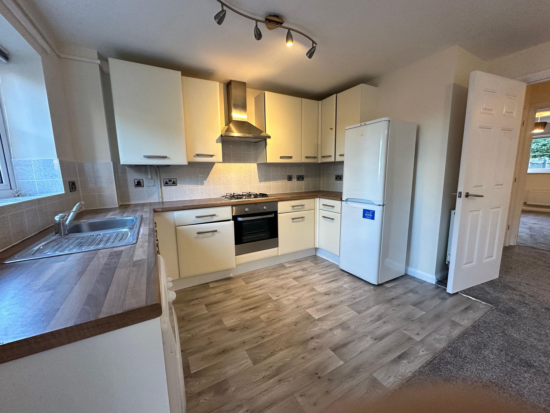 Fitted kitchen with gas hob, oven, extractor and fridge freezer